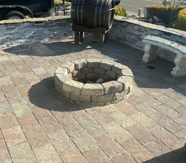Firepit in the middle of a stone patio with stone walls surrounding it